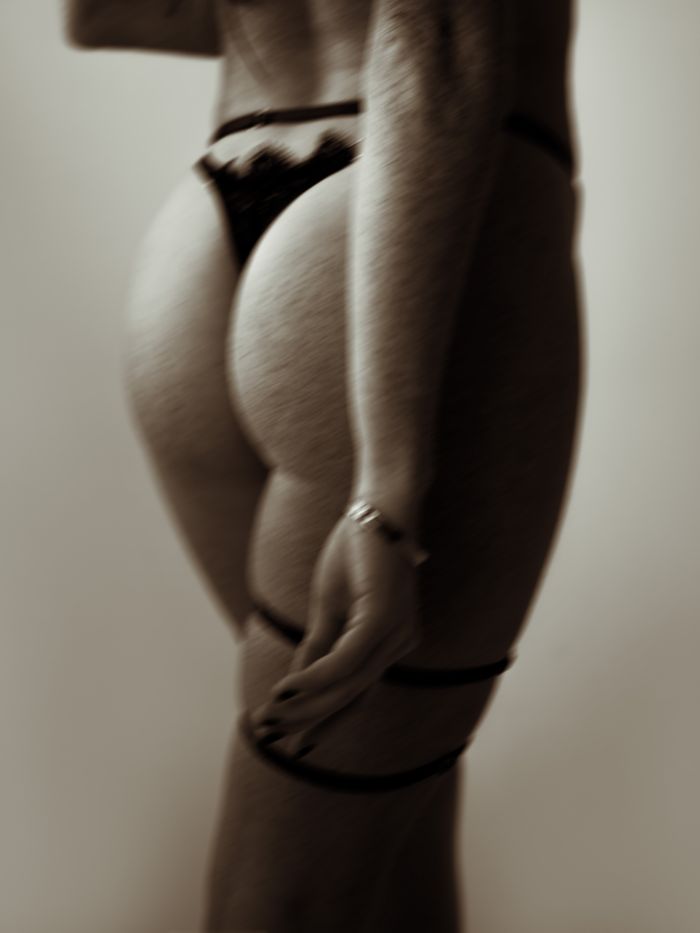 Elegant image capturing a sultry pose in lace lingerie with soft sepia tones.