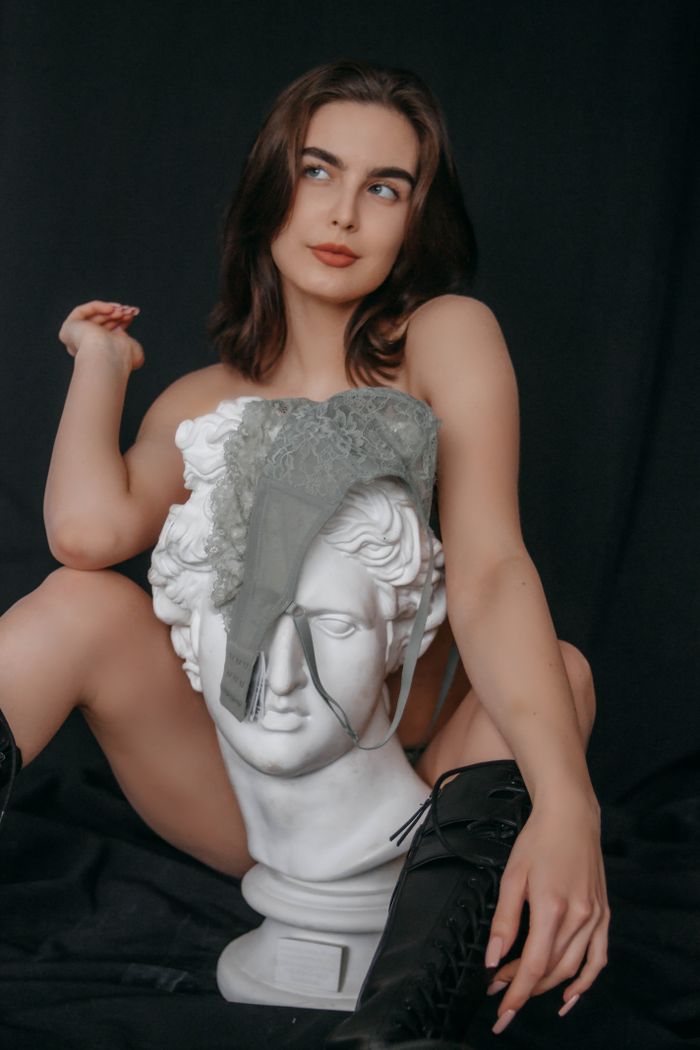 Woman with lace and statue, an artistic and bold representation in a studio setting.